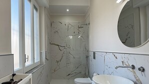 Un baño moderno con un lavamanos ovalado grande, un inodoro y una ducha.