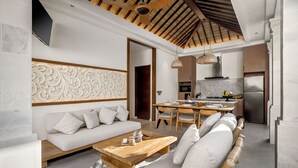 A modern living room with a sofa, a wooden coffee table, and a dining area with a table and chairs. - Villa Advaya (Kerobokan)