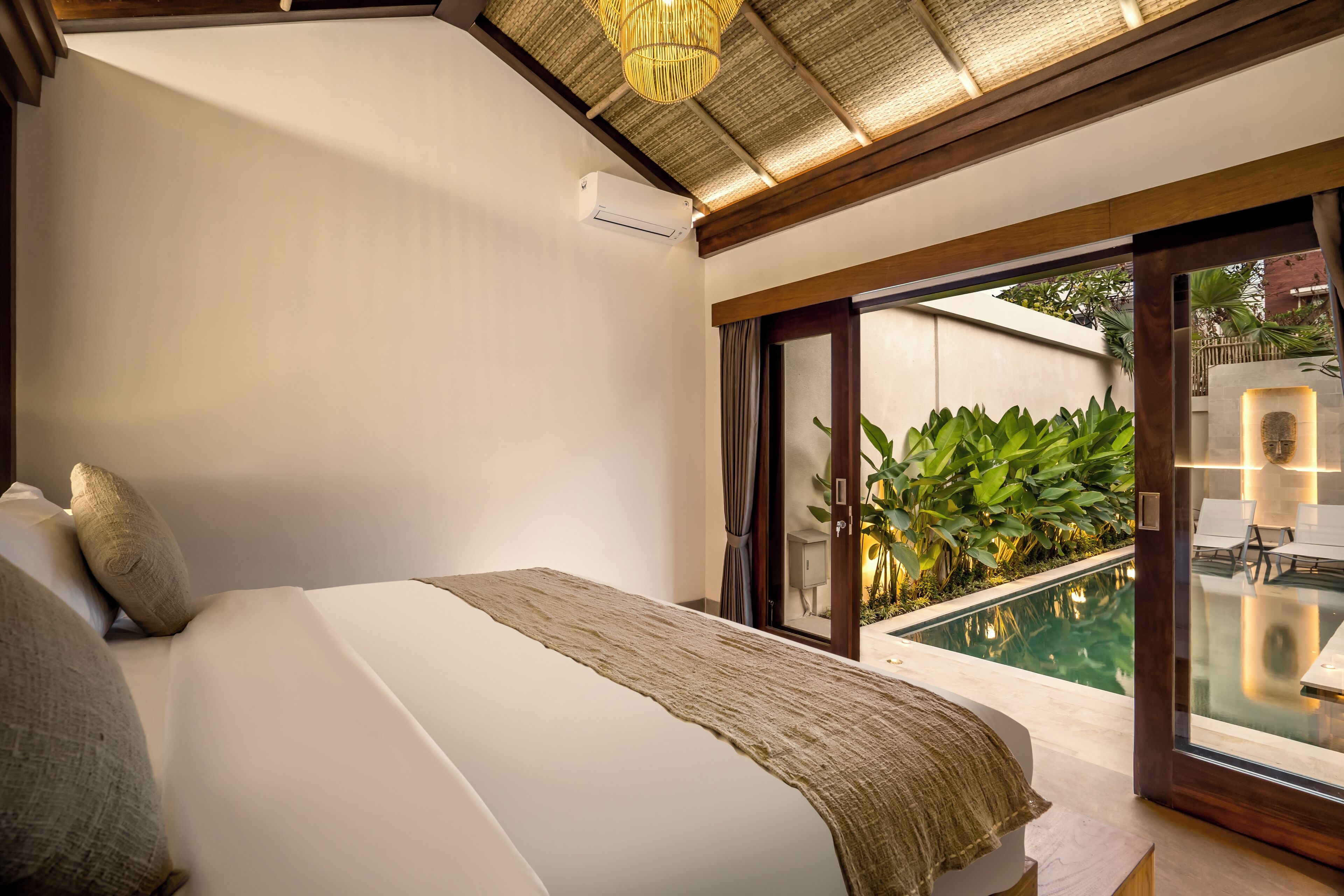 A bedroom with a large bed, a view of a swimming pool, and a ceiling fan.