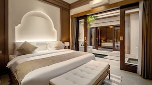 A spacious bedroom with a large bed, a wooden headboard, and a view of a pool area. - Villa Advaya (Kerobokan)