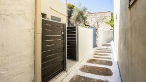 Une ruelle étroite, bordée d’un côté par un immeuble moderne et de l’autre par un mur de pierre.