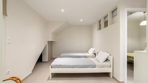 Une chambre avec deux lits, une chaise et un petit bureau.
