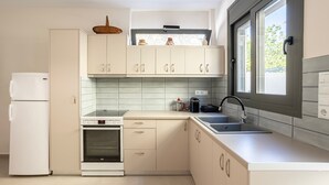 Une cuisine moderne avec des armoires blanches, un four encastré, un évier et une fenêtre donnant sur l’extérieur.