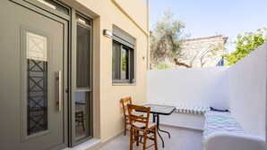 Une petite terrasse extérieure avec une table et des chaises, un canapé et une porte-fenêtre coulissante.