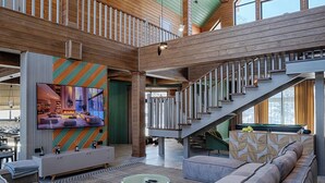 A spacious living area with a large sofa, a flat-screen TV, and a staircase leading to an upper level. - Park-Hotel Zarechye  (Bystrukha)