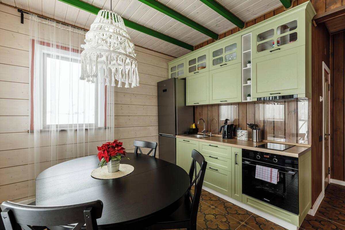 Una cocina con armarios verdes, un refrigerador negro y un horno empotrado.
