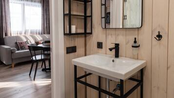 Een moderne badkamer met een wit wastafelmeubel, zwarte planken en een spiegel.