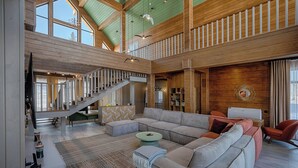 A spacious living area with a large sectional sofa, a staircase, and a wooden ceiling. - Park-Hotel Zarechye  (Bystrukha)