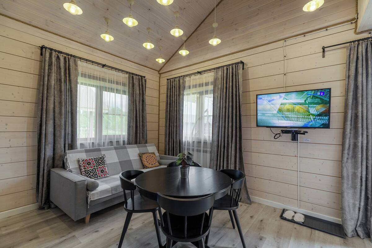Una habitación acogedora con un sofá, una mesa redonda y un televisor montado en la pared.