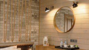 A bedroom with a wooden headboard, a round mirror, a wooden dresser with toiletries, and hanging woven light fixtures. - Park-Hotel Zarechye  (Bystrukha)