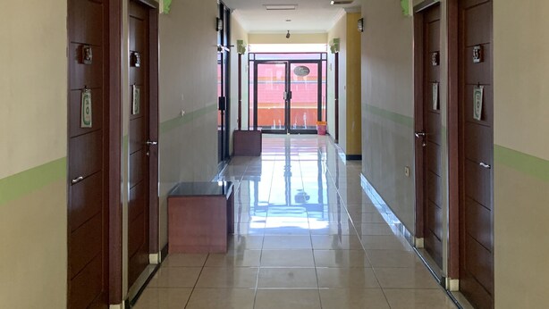 A hotel corridor with a tiled floor, wooden doors, and green decorative moldings. - Hotel O Depok near Bhayangkara BRIMOB Hospital Formerly Hotel Mutiara Kelapa Dua Depok (Depok)
