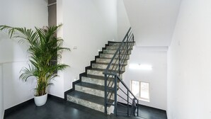 Uma escadaria com corrimão de metal, um vaso de planta e uma janela no patamar.