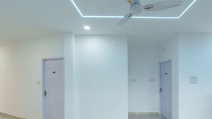 Um corredor com paredes brancas, um ventilador de teto e duas portas.