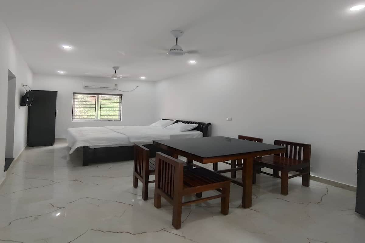 A room with a bed, a table with chairs, a ceiling fan, and a window with blinds.