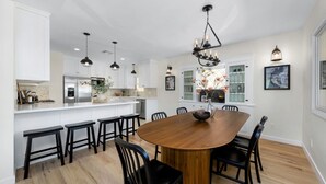 Une cuisine moderne avec des meubles blancs, un îlot central et des luminaires suspendus.