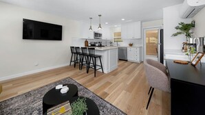 A modern kitchen with white cabinets, a central island, and bar stools.