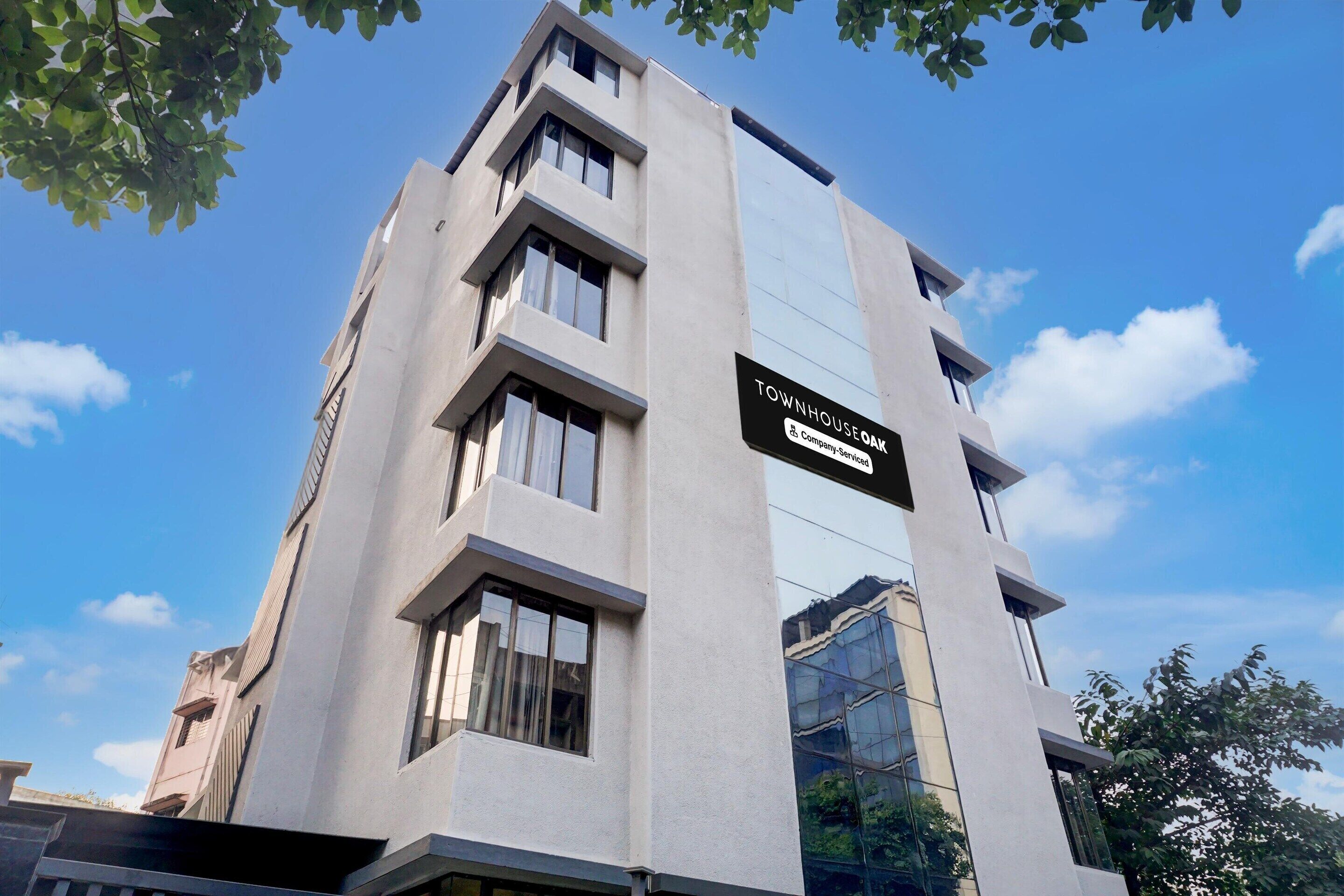 A modern building with a sign reading "Townhouse Oak" and "Company Service."