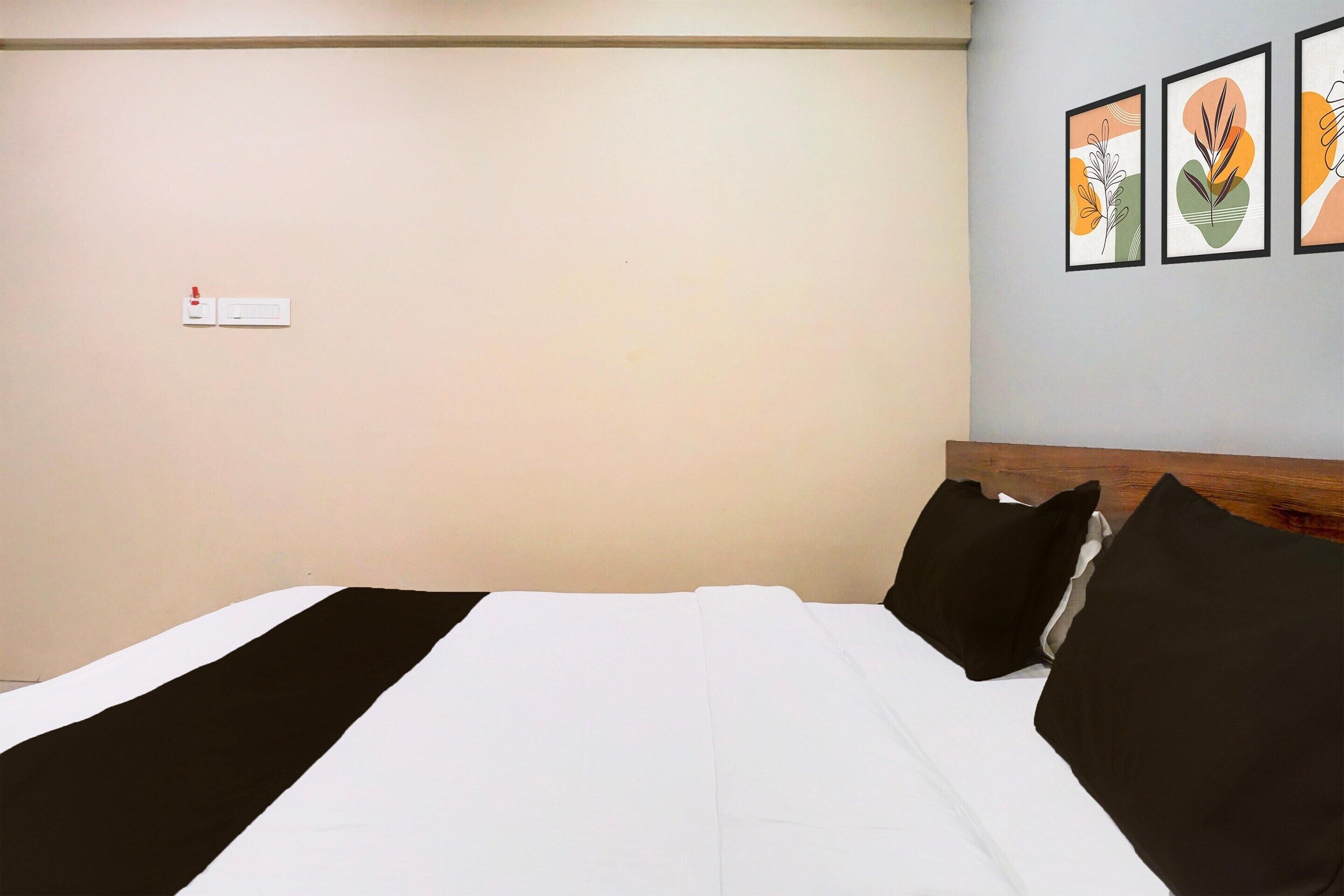 Une chambre d’hôtel avec un lit, une tête de lit et trois œuvres d’art encadrées accrochées au mur.