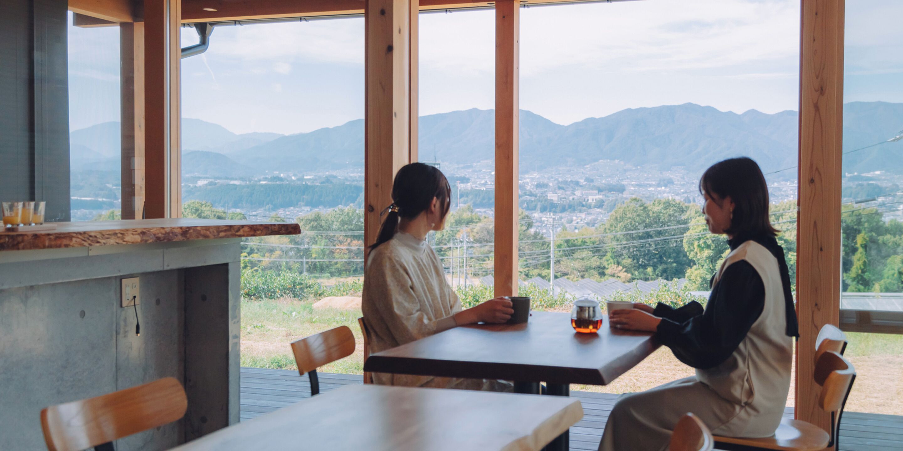 Two people seated at a table with a view of mountains and a city in the background.