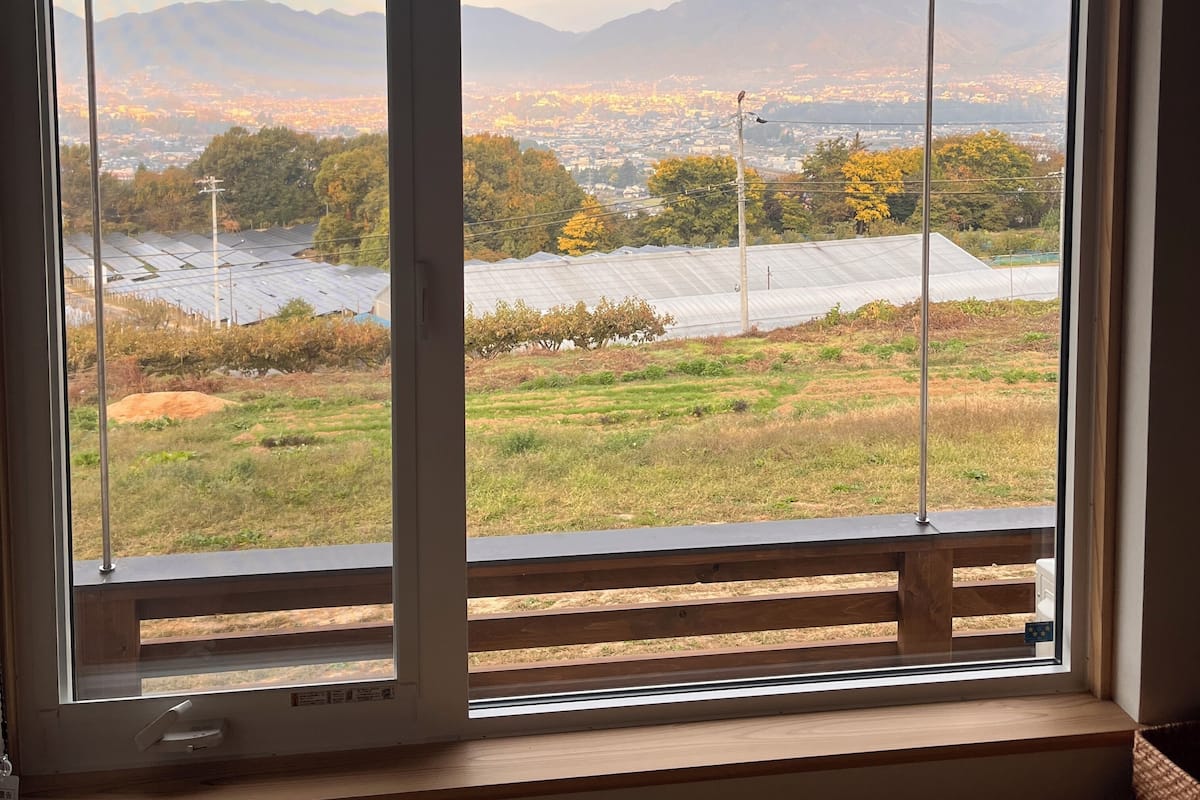 A window with a view of a cityscape, mountains, and agricultural fields.