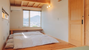 A bedroom with a large window, wooden beams, and a bed with white bedding. - Cider Barn &more (Iida)