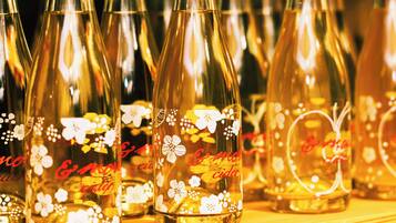 A collection of clear glass bottles with floral designs and the text "C&M Cider" on them.
