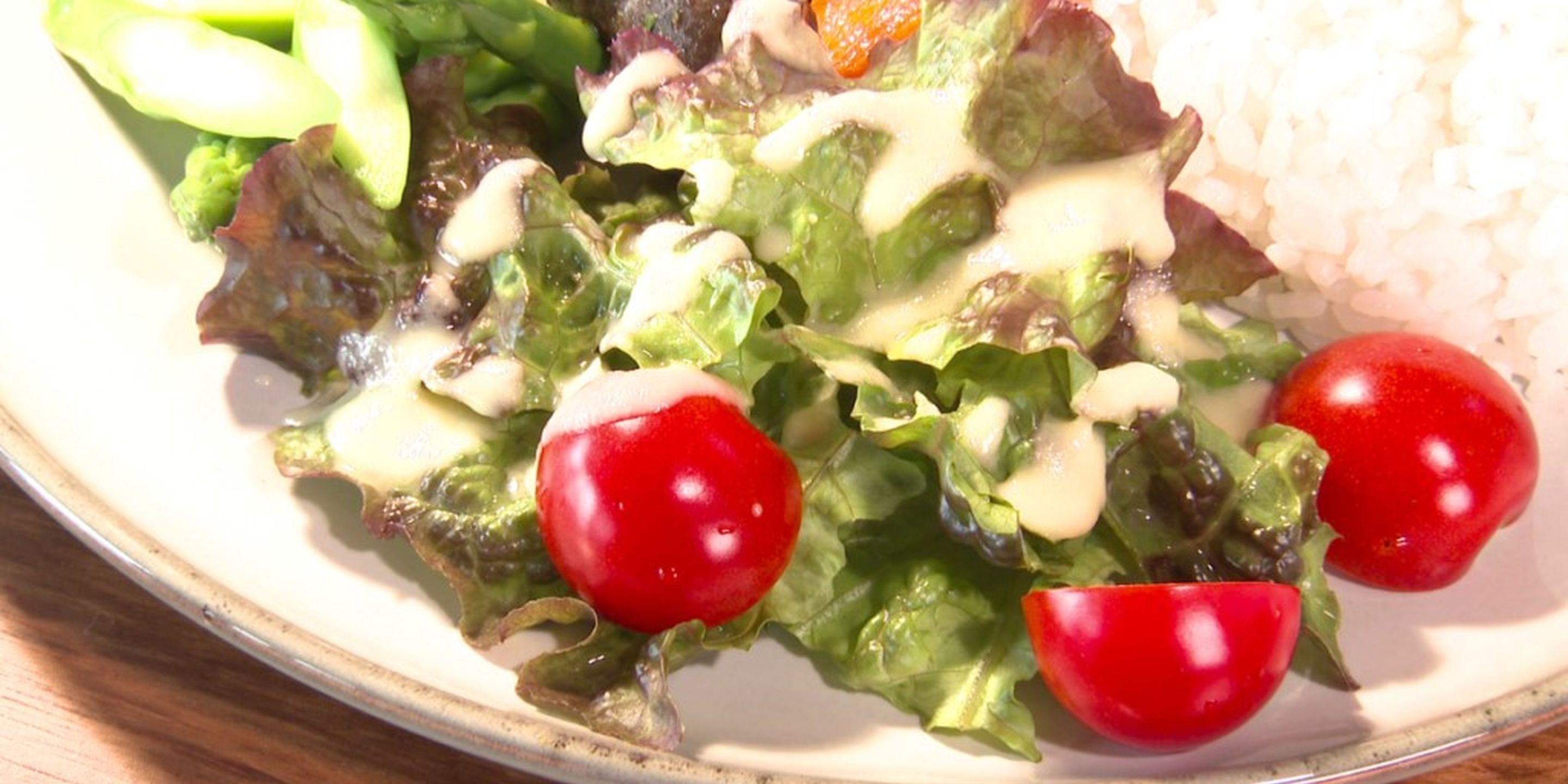 A plate with a salad, cherry tomatoes, and rice.