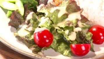 A plate with a salad, cherry tomatoes, and rice.
