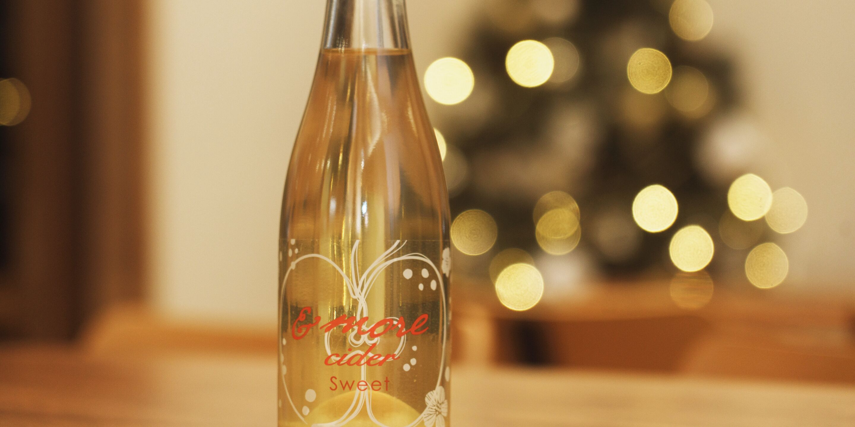 A bottle of Erroneous Cider Sweet with a blurred background featuring bokeh lights.