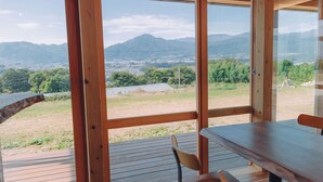 A wooden deck with a table and chairs overlooking a mountainous landscape. - Cider Barn &more (Iida)