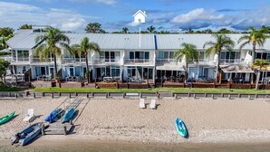 Un hotel frente a la playa con varios balcones, una playa de arena y varios barcos.