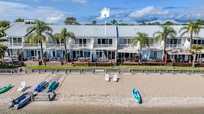 Ein Strandhotel mit mehreren Balkonen, einem Sandstrand und verschiedenen Booten.