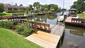 A marina with wooden docks, benches, and a small boat docked. - Salty Breeze Canal Front Pool Home W Boat Dock (Palm Coast)