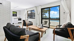 A modern living room with a view of the sea, a dining area, and a kitchen.