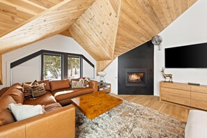 Ein moderner Loftsitz mit hohen Decken, Kamin, einer Sofagarnitur und einem Fernseher.