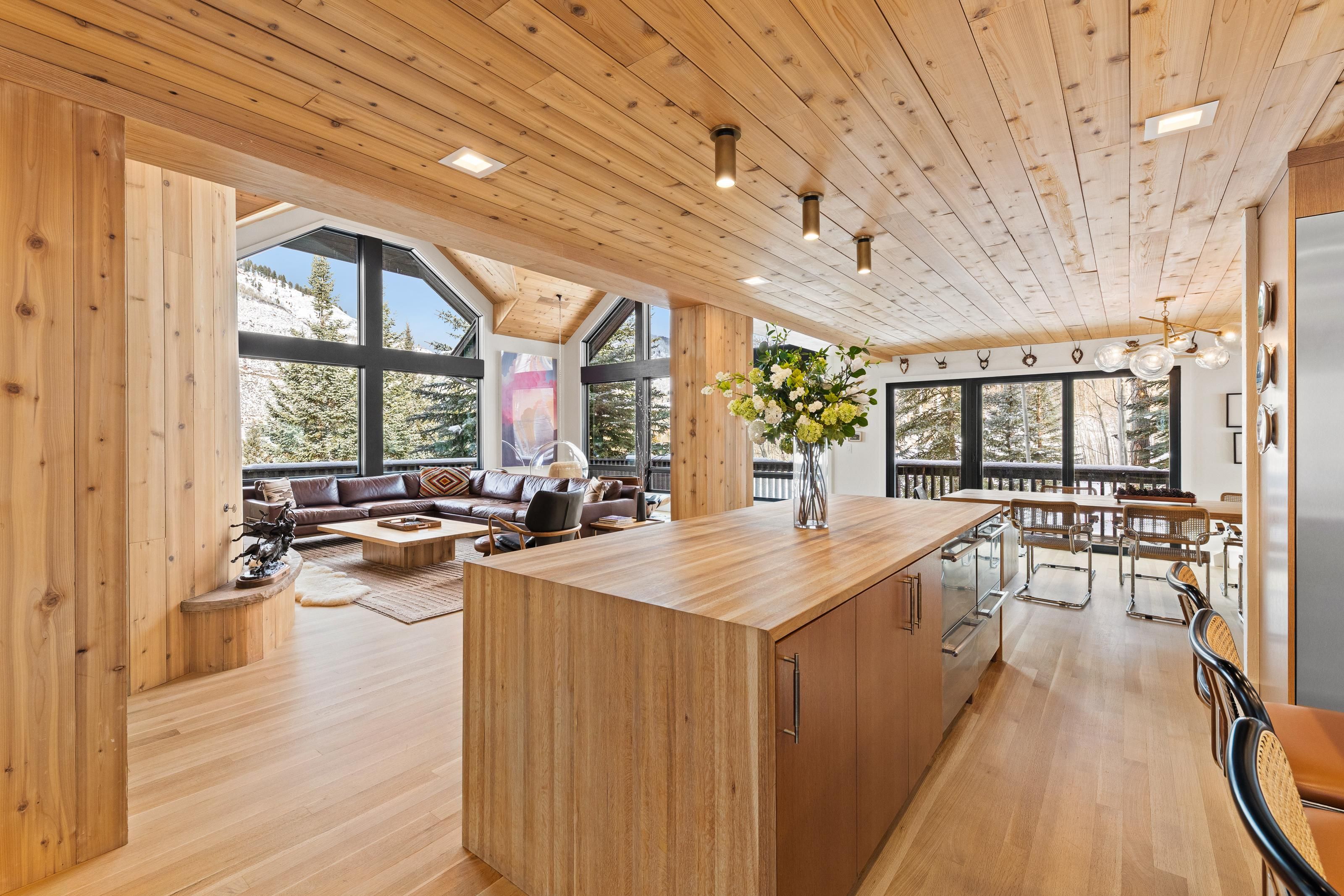 A spacious living area with a wooden floor, a central island, and a large window overlooking a snowy landscape.