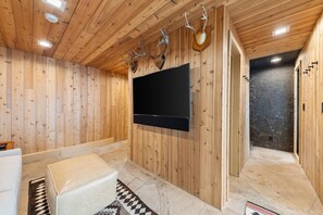 Ein Holzinnenraum mit montiertem Fernseher, Steinboden und Steinwand.