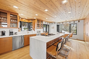 A modern kitchen with wooden cabinetry, a central island, and a bar area with bar stools.