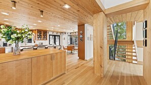 Una cocina moderna con armarios de madera, una isla central y un comedor con vistas al exterior.