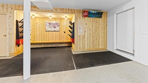 Una habitación con paredes de madera, un letrero de Coors colgado, una puerta y un banco.