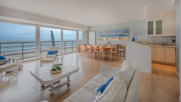 A spacious living area with a large window overlooking the sea, a dining area, and a kitchen. - Spacious 9-guest Knokke Apt (Knokke-Heist)