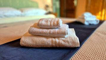 A neatly made bed with folded towels and a dark blue bedspread.
