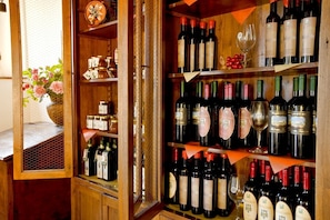 Una bodega con estantes de madera llenos de diferentes botellas de vino y copas.