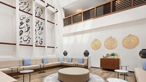 A modern lounge area with a sectional sofa, round ottoman, and small tables.