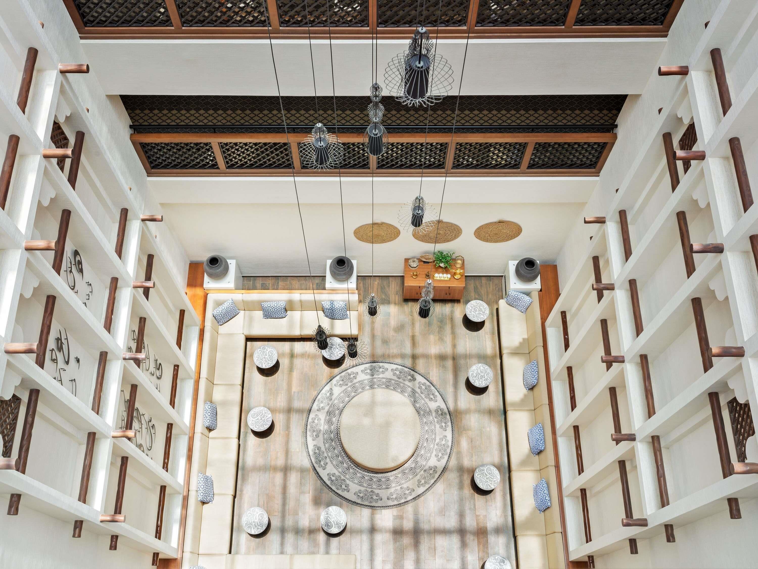 Un intérieur spacieux agrémenté d’un grand tapis décoratif, de luminaires suspendus et d’une structure de plafond en bois.