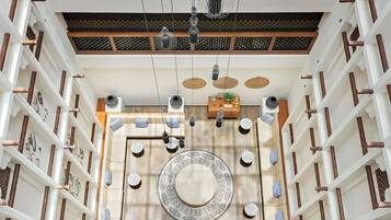 Un intérieur spacieux agrémenté d’un grand tapis décoratif, de luminaires suspendus et d’une structure de plafond en bois.