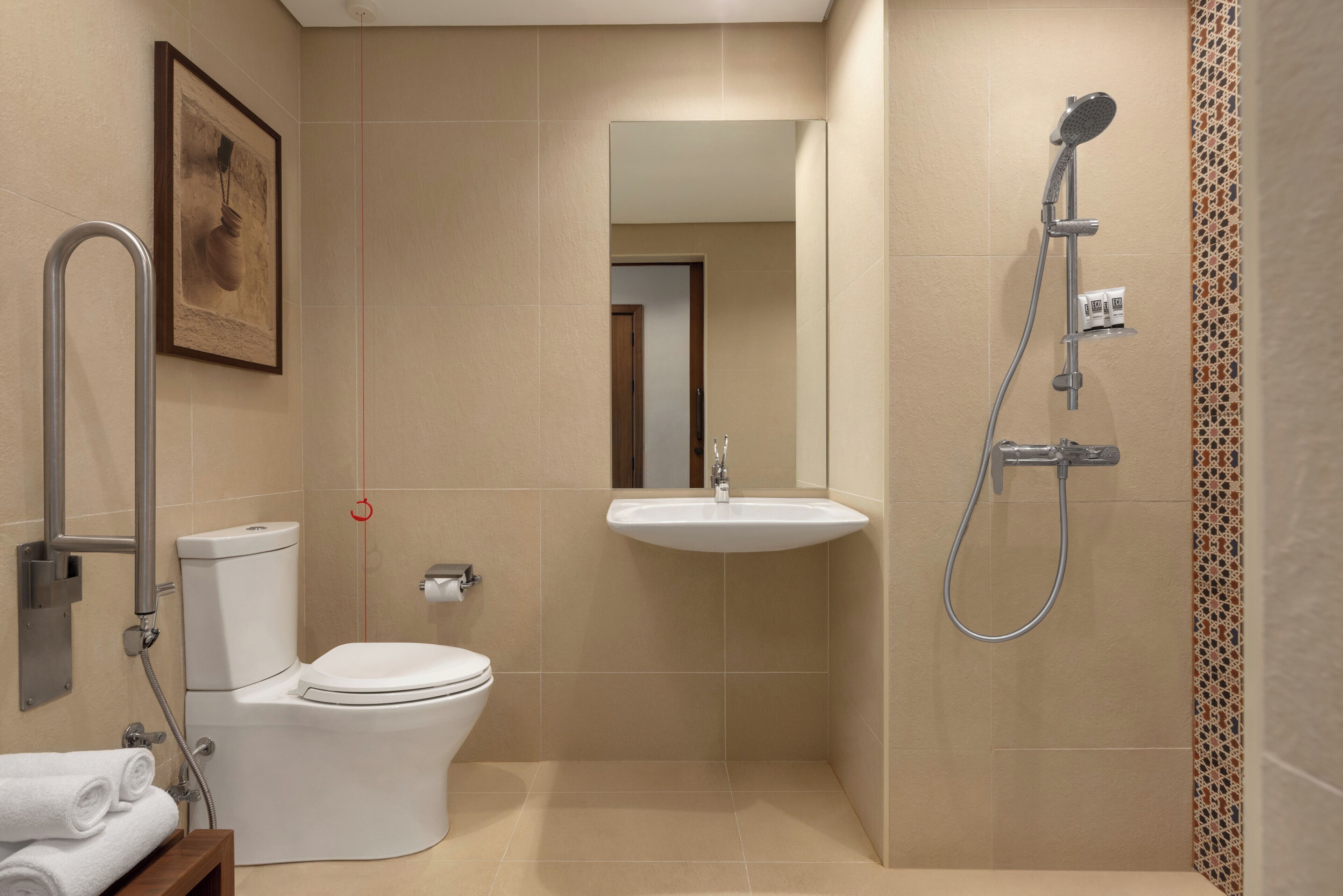 Une salle de bain équipée de toilettes, d’un lavabo, d’une douche et d’un tableau encadré au mur.