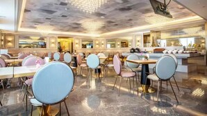 A spacious dining area with round tables and chairs, a modern chandelier, and a large mirror reflecting the room. - Mercure Changchun Ziyou Road Dahua (Changchun)