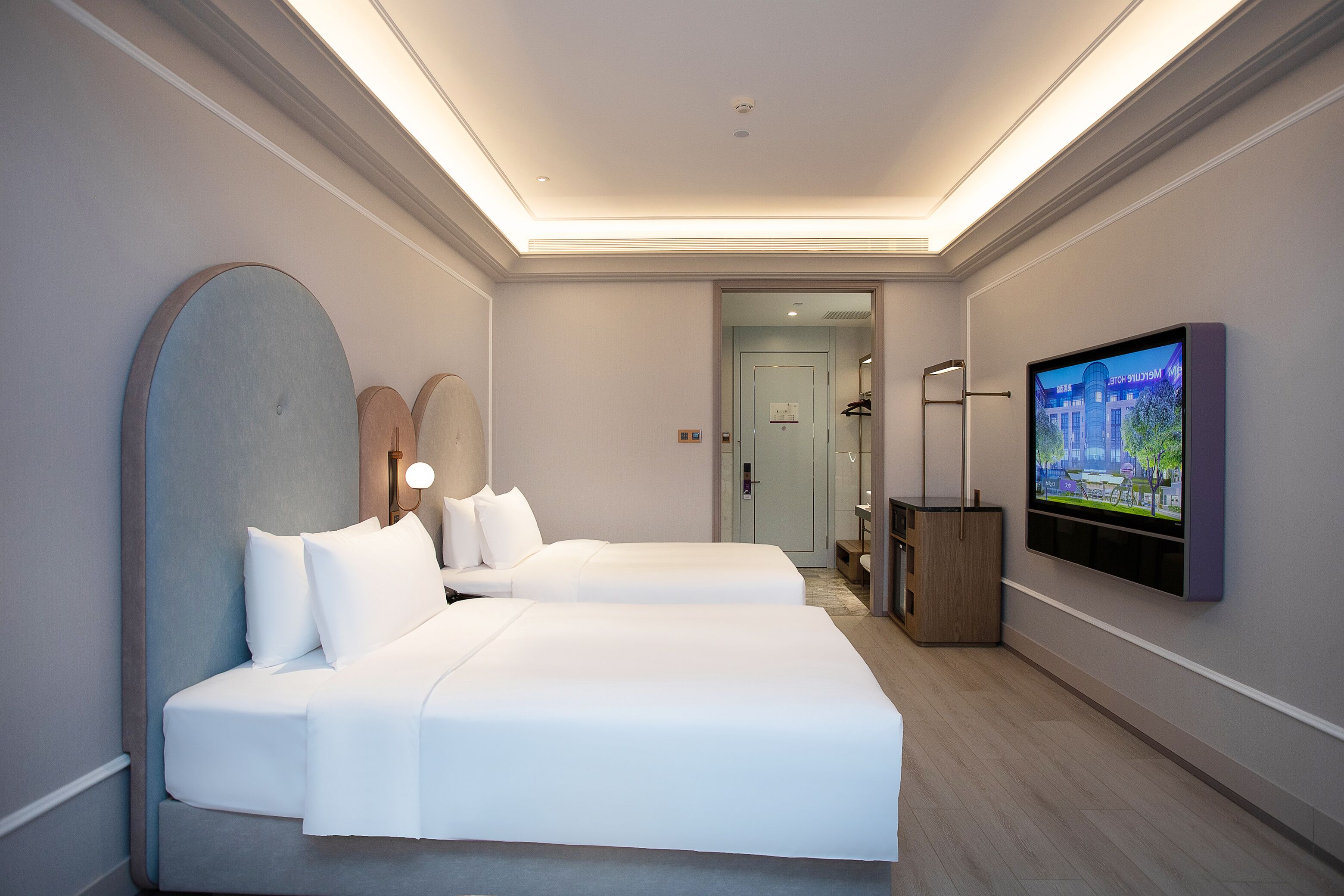 A modern hotel room with two beds, a television, and a walk-in closet.
