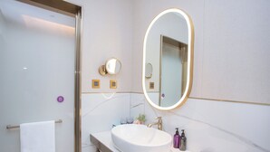 A modern bathroom with a large oval mirror, a white sink, and a towel rack. - Mercure Changchun Ziyou Road Dahua (Changchun)